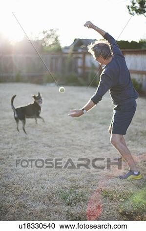 Stock Image - Senior Caucasian man plays with a dog. Fotosearch