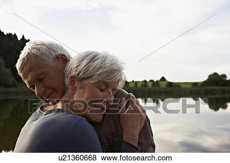 Senior couple hugging in front of lake View Large Photo Image Stock Photo - Senior couple hugging in front of lake. Fotosearch