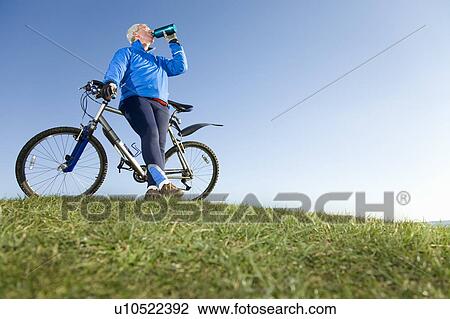 Stock Image - Senior man drinking water on bike ride. Fotosearch