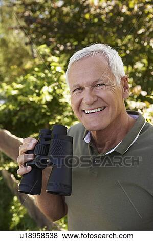 Stock Photo - Senior man holding binoculars. Fotosearch