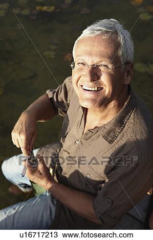 Stock Image - Senior man opening bottle of wine. Fotosearch