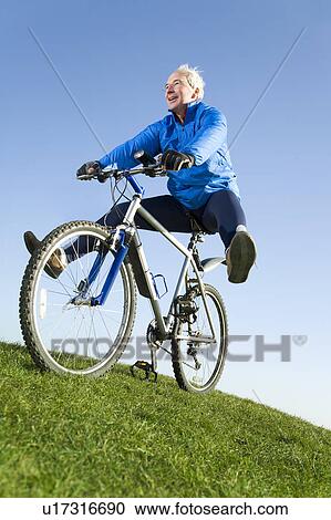 Stock Image - Senior man riding mountain bike. Fotosearch
