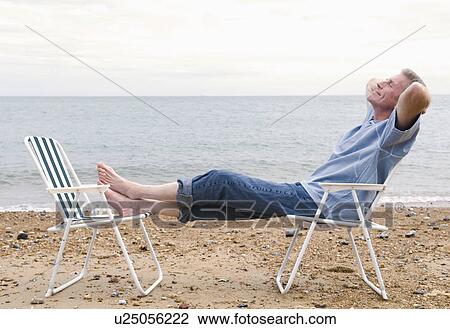 Stock Image - Senior relaxes on beach. Fotosearch
