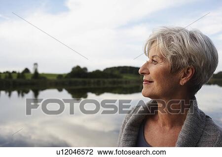 Stock Image - Senior woman watching sunset. Fotosearch