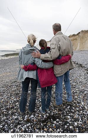 Stock Image - Seniors and grandchild on beach. Fotosearch