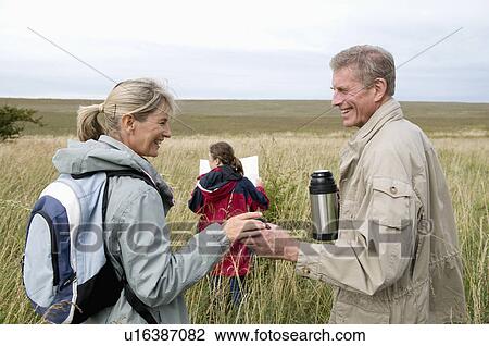 Stock Image - Seniors and grandchild pause on walk. Fotosearch
