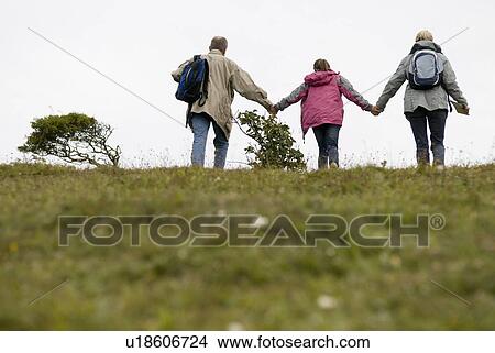Picture - Seniors and granddaughter climb hill. Fotosearch