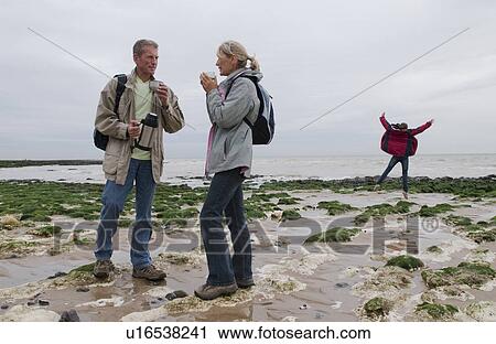 Stock Image - Seniors take a break on beach and child. Fotosearch