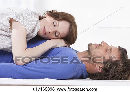 Stock Photo - Side view of couple relaxing on rug. Fotosearch