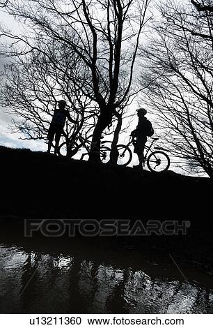 Silhouette couple biking in countryside View Large Photo Image Stock Image - Silhouette couple biking in countryside. Fotosearch