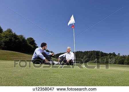 Stock Photo - Sitting together on the putting green. Fotosearch