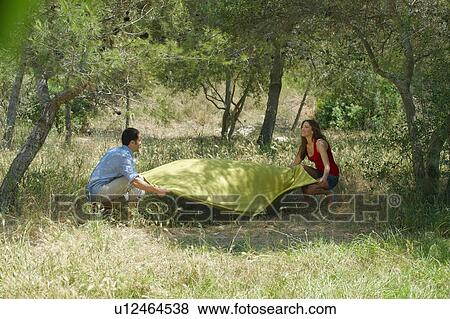 Stock Photo - Smiling couple laying out picnic blanket. Fotosearch