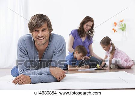 Smiling man on rug family in background View Large Photo Image Picture - Smiling man on rug family in background. Fotosearch