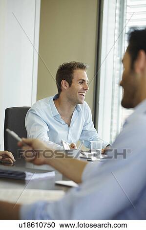 Stock Image - Smiling young man in business meeting. Fotosearch