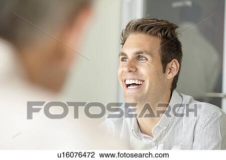 Stock Image - Smiling young man in meeting. Fotosearch