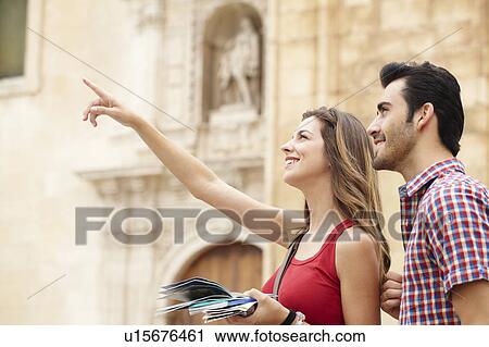 Stock Image - Smiling young woman pointing out sights. Fotosearch