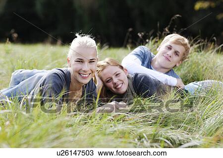 Three young persons laying in grass View Large Photo Image Stock Image - Three young persons laying in grass. Fotosearch