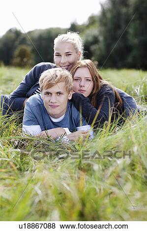 Three young persons laying in grass View Large Photo Image Stock Photo - Three young persons laying in grass. Fotosearch