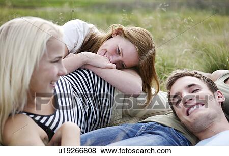 Three young persons laying in grass View Large Photo Image Stock Photo - Three young persons laying in grass. Fotosearch