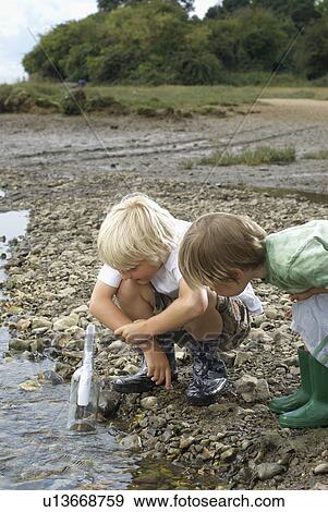 Stock Photo - Two boys finding a message in a bottle. Fotosearch