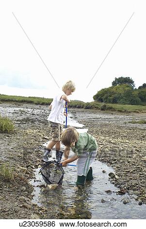Two boys fishing with nets in a stream View Large Photo Image Stock Photograph - Two boys fishing with nets in a stream. Fotosearch