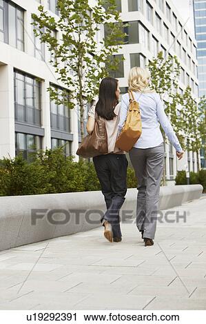 Two business women walking on sidewalk View Large Photo Image Stock Image - Two business women walking on sidewalk. Fotosearch