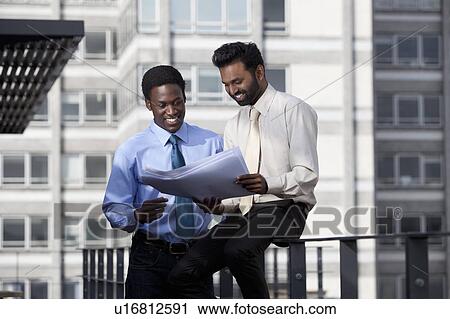 Two businessmen looking at paper lans View Large Photo Image Stock Image - Two businessmen looking at paper lans. Fotosearch