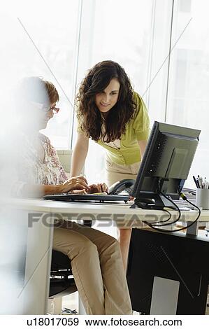 Two female colleagues working in office View Large Photo Image Stock Photo - Two female colleagues working in office. Fotosearch