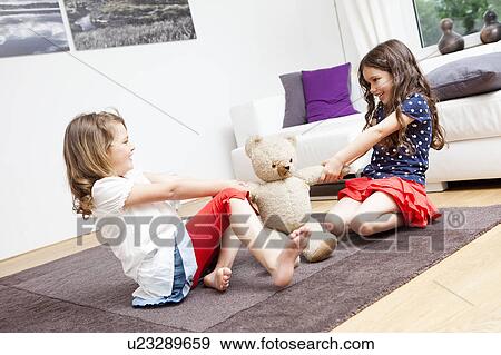 Stock Photo - Two girls battle for a teddy bear. Fotosearch