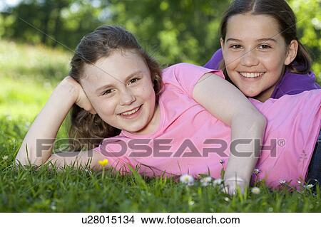 Picture - Two girls resting in meadow, happy. Fotosearch
