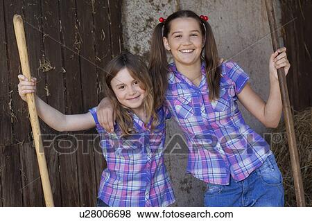 Stock Photo - Two girls resting on hayforks. Fotosearch