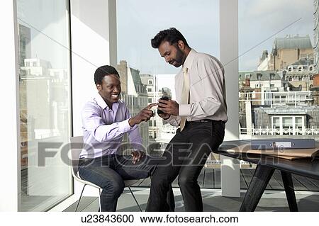 Two men discussing mobile telephone View Large Photo Image Stock Image - Two men discussing mobile telephone. Fotosearch