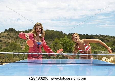 Stock Image - Two women playing table tennis outdoors. Fotosearch