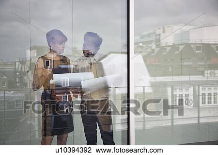 Two work colleagues discuss paperwork View Large Photo Image Stock Image - Two work colleagues discuss paperwork. Fotosearch