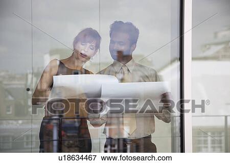 Two work colleagues discussing paperwork View Large Photo Image Stock Photo - Two work colleagues discussing paperwork. Fotosearch