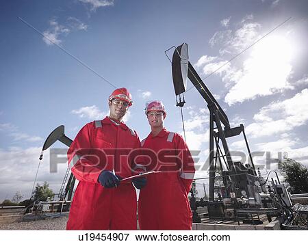 Stock Photo - Two workers in front of oil wells. Fotosearch