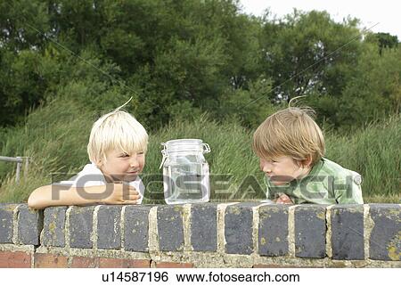 Two young boys looking at fish in a jar View Large Photo Image Stock Photograph - Two young boys looking at fish in a jar. Fotosearch