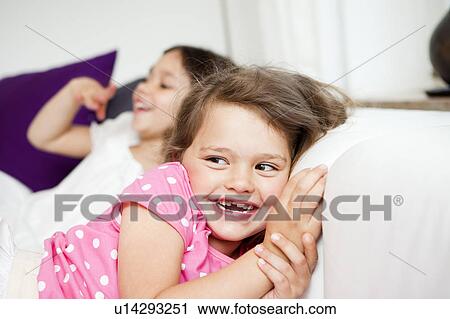 Stock Image - Two young Girls having fun on couch. Fotosearch