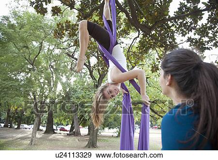 Stock Photo - Two young woman doing acrobatics in tree. Fotosearch