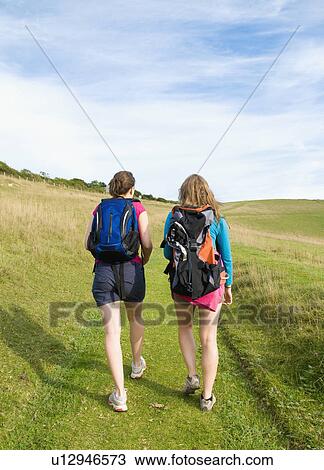 Two young women hikers climb up hill View Large Photo Image Stock Image - Two young women hikers climb up hill. Fotosearch