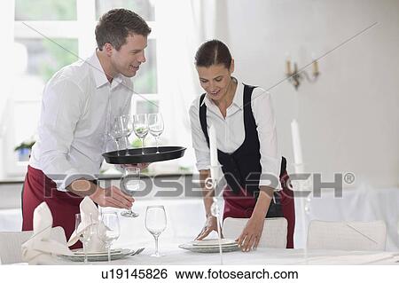 Stock Photograph - Waiter and waitress laying the table. Fotosearch