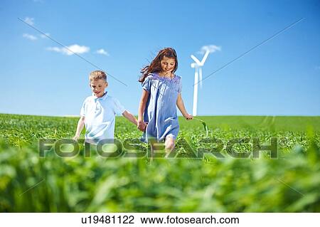 Stock Image - Wind turbine, boy and girl on field. Fotosearch
