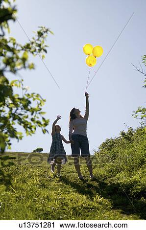 Stock Image - Woman and child look at balloons. Fotosearch