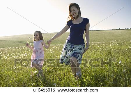 Stock Photography - Woman and child walk thru sunny meadow. Fotosearch