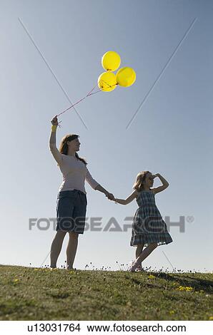 Picture - Woman and child with balloons on hill. Fotosearch