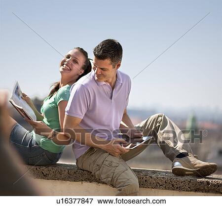 Stock Photo - Woman and man sitting on wall. Fotosearch