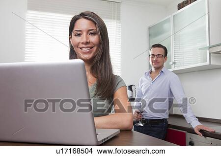 Picture - Woman and man using laptop at home. Fotosearch