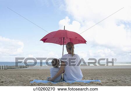 Stock Image - Woman and son under a parasol. Fotosearch