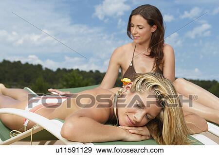 Woman applying sunblock on female friend View Large Photo Image Stock Photo - Woman applying sunblock on female friend. Fotosearch