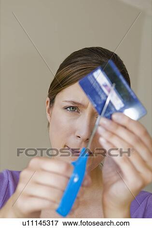 Stock Photo - Woman cuts up credit card. Fotosearch